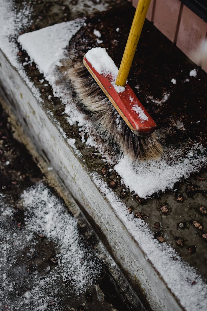 A broom clearing snow from outdoor steps in Estonia during winter.